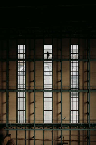 tiny couple standing in front of window in old factory building