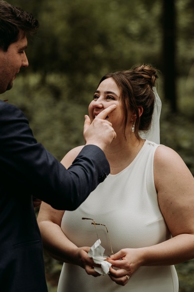 groom wiping away tear from bride's cheek