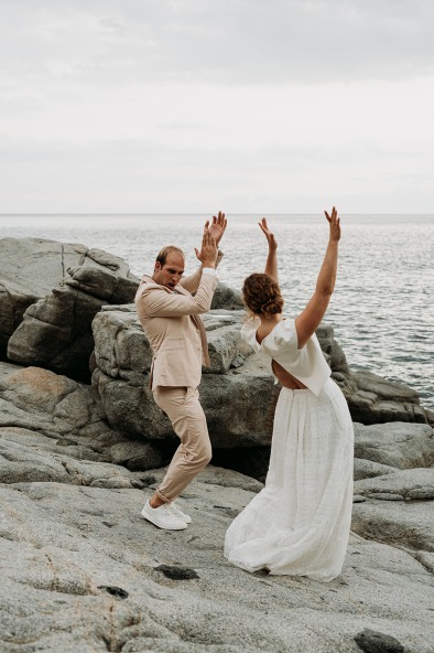 bride and groom dancing on rocky coastline