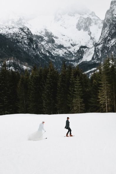 newly weds snowboarding and skiing down the mountain