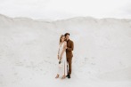 bride and groom posing in front of white sand