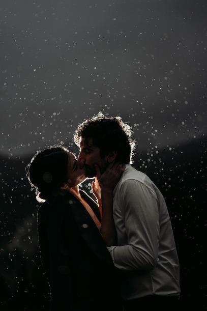 backlit couple kissing in the rain