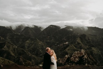 married couple hugging in cloudy mountain landscape