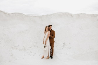 bride and groom posing in front of white sand