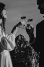 out of focus couple clinking glasses in front of mountain